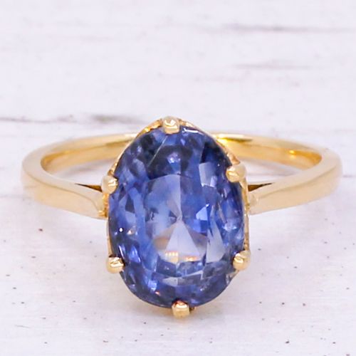 fig 2. A mid-century yellow gold solitaire ring featuring a large oval cut blue sapphire in a six-prong basket setting.