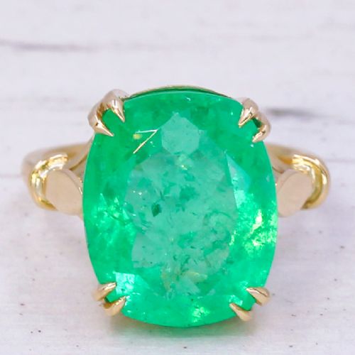 fig 2. A mid-century yellow gold solitaire ring featuring a large cushion-cut green emerald secured with double claw settings.