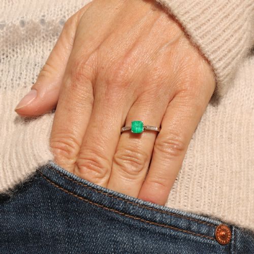 fig 1. An Art Deco ring featuring a square-cut green emerald solitaire set in a platinum band with small diamond shoulders.
