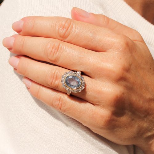 fig 1. A mid-century cluster ring showcasing a prominent oval blue sapphire framed by a halo of rose-cut diamonds set on a gold band.