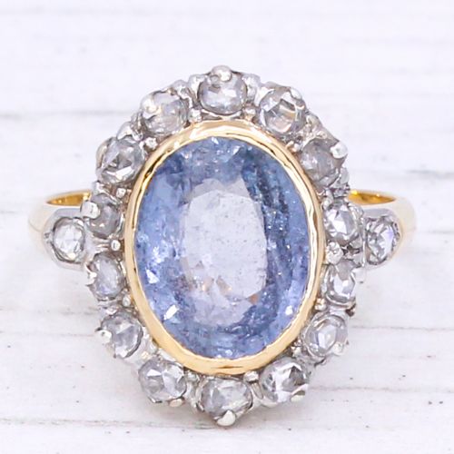 fig 2. A mid-century cluster ring showcasing a prominent oval blue sapphire framed by a halo of rose-cut diamonds set on a gold band.