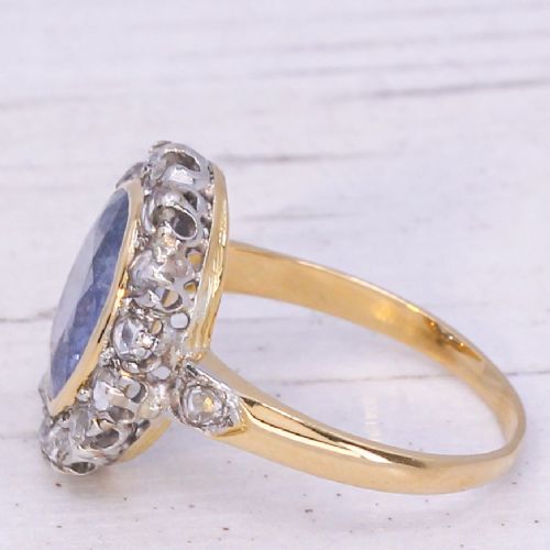 fig 3. A mid-century cluster ring showcasing a prominent oval blue sapphire framed by a halo of rose-cut diamonds set on a gold band.