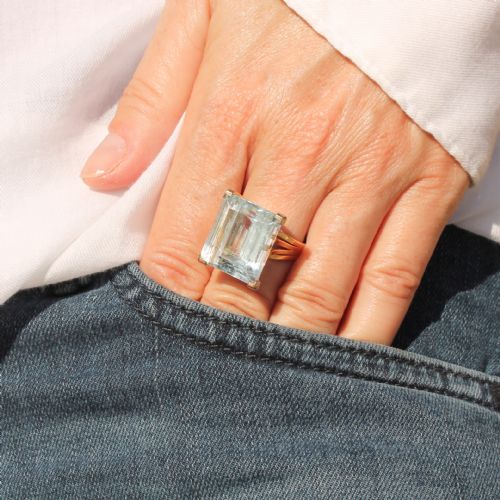 fig 1. A large emerald-cut light blue aquamarine gemstone set in a yellow gold solitaire mount with split shoulders.