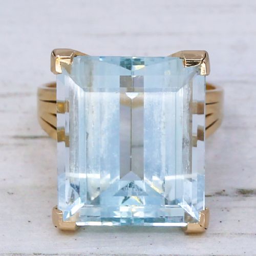 fig 2. A large emerald-cut light blue aquamarine gemstone set in a yellow gold solitaire mount with split shoulders.
