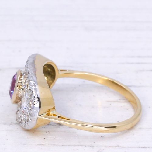 fig 3. A vintage gold ring featuring a central bezel-set pink sapphire flanked by two round diamonds within a pave-set diamond oval plaque.