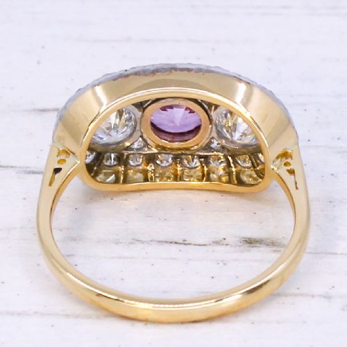 fig 4. A vintage gold ring featuring a central bezel-set pink sapphire flanked by two round diamonds within a pave-set diamond oval plaque.