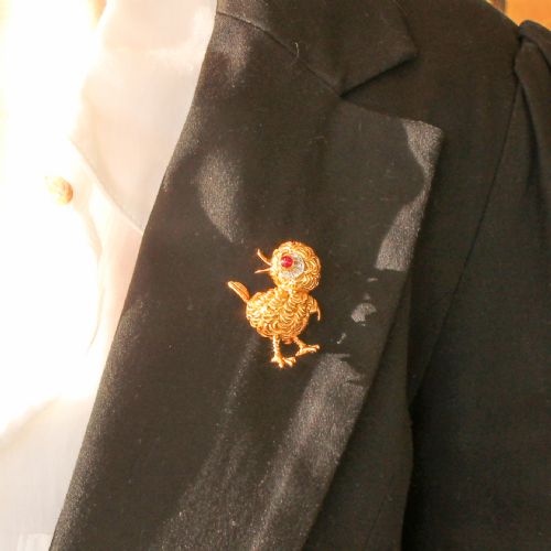 fig 1. A textured yellow gold chick brooch featuring a cabochon ruby eye framed by small diamonds.