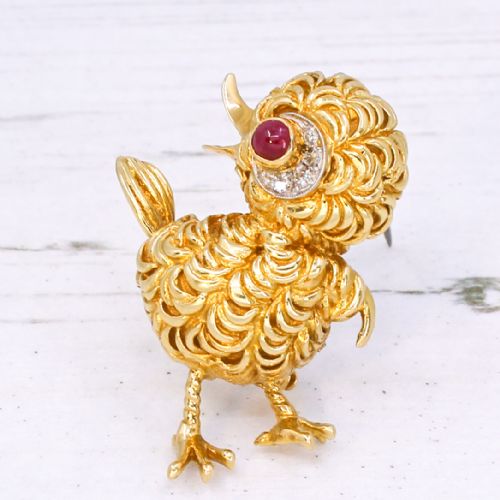 fig 2. A textured yellow gold chick brooch featuring a cabochon ruby eye framed by small diamonds.