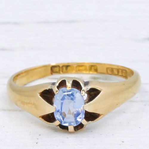fig 2. An antique yellow gold ring featuring a central oval pale blue sapphire set in claw mountings with hallmarks engraved inside the band.