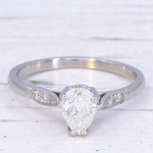 fig 2. A vintage platinum ring featuring a central pear-cut diamond in a prong setting with small diamond accents on the shoulders.