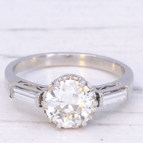 fig 2. A vintage platinum engagement ring featuring a central round old cut diamond flanked by two tapered baguette diamonds.