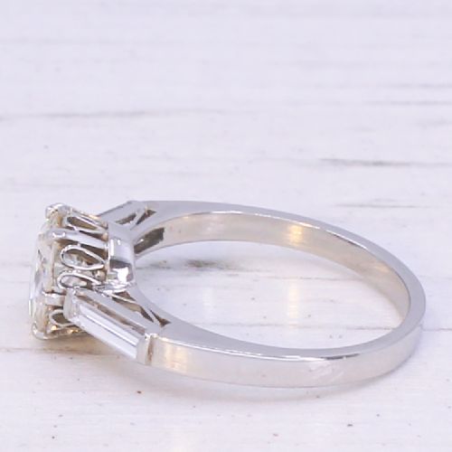 fig 3. A vintage platinum engagement ring featuring a central round old cut diamond flanked by two tapered baguette diamonds.