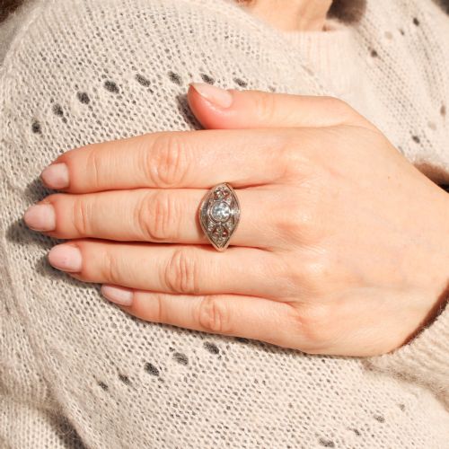fig 1. An Art Deco platinum ring featuring a central round old cut diamond in a bezel setting surrounded by pierced filigree scrollwork and small accent diamonds.