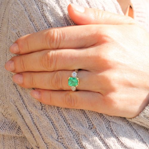 fig 1. A vintage gold ring set with a rectangular central emerald-cut green gemstone and two flanking round brilliant diamonds.