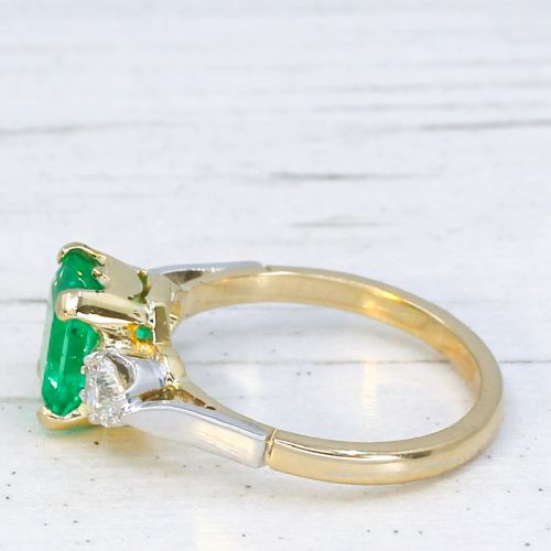 fig 3. A vintage gold ring set with a rectangular central emerald-cut green gemstone and two flanking round brilliant diamonds.
