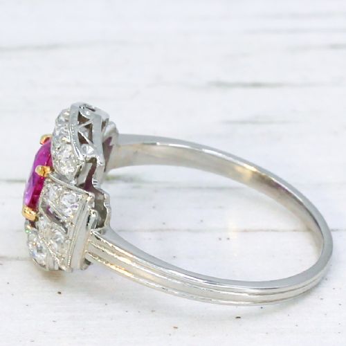 fig 3. An Art Deco platinum ring featuring an oval pink sapphire in a four-claw setting surrounded by a geometric halo of diamonds with milgrain detail.