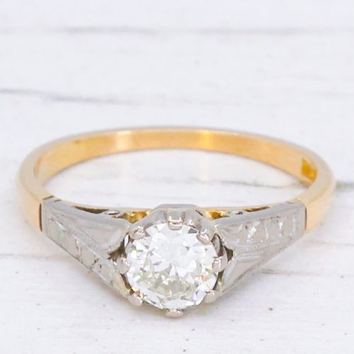 fig 2. A vintage yellow gold solitaire engagement ring featuring a round brilliant cut diamond set in white metal claws with carved shoulders.