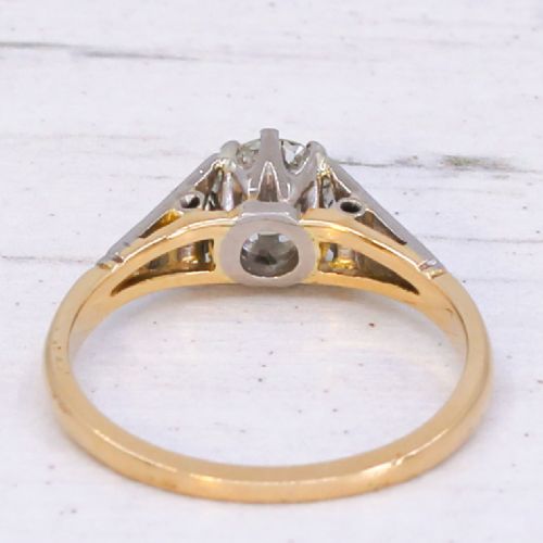A vintage yellow gold solitaire engagement ring featuring a round brilliant cut diamond set in white metal claws with carved shoulders. View V