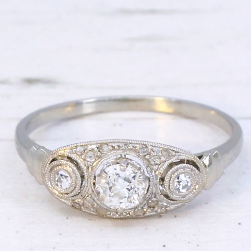 fig 2. A vintage Art Deco white metal ring featuring a central old cut diamond flanked by two smaller diamonds in an elongated milgrained setting.