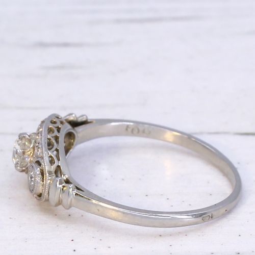 fig 3. A vintage Art Deco white metal ring featuring a central old cut diamond flanked by two smaller diamonds in an elongated milgrained setting.