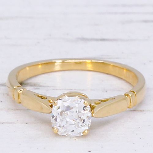 fig 2. A yellow gold solitaire ring featuring a central cushion shaped old cut diamond with geometric shoulder accents.