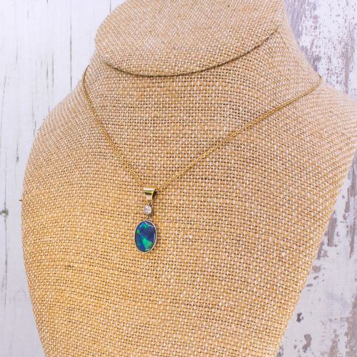 fig 3. An Edwardian black opal and diamond pendant featuring an oval cabochon opal with blue and green play-of-colour mounted in gold below a bezel-set diamond.