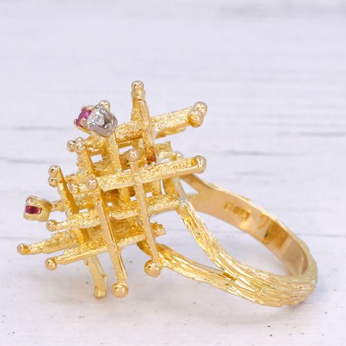 fig 3. A 1960s textured yellow gold ring featuring an abstract lattice structure set with two round rubies and a single clear diamond.