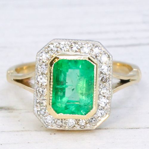 fig 2. A vintage gold ring featuring a central rectangular green emerald surrounded by a halo of small diamonds.