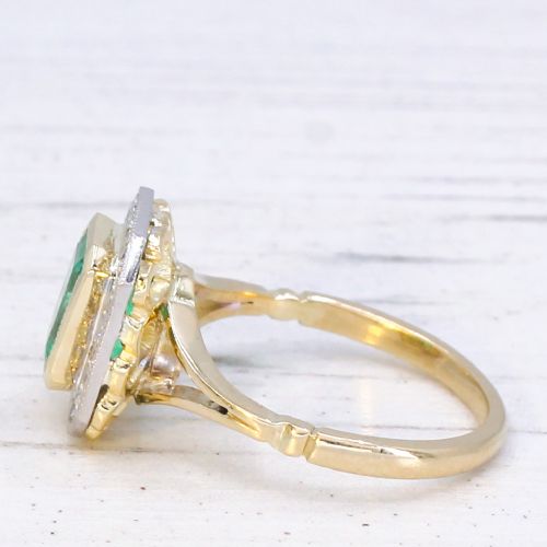 fig 3. A vintage gold ring featuring a central rectangular green emerald surrounded by a halo of small diamonds.