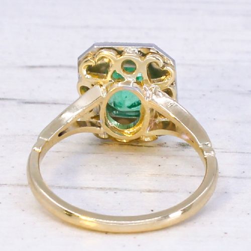 fig 4. A vintage gold ring featuring a central rectangular green emerald surrounded by a halo of small diamonds.