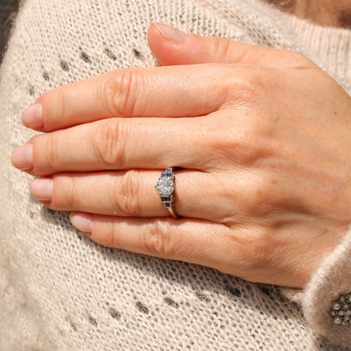 fig 1. A platinum ring featuring a central round old cut diamond flanked by stepped calibre-cut blue sapphires.