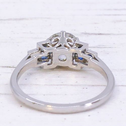 A platinum ring featuring a central round old cut diamond flanked by stepped calibre-cut blue sapphires. View V