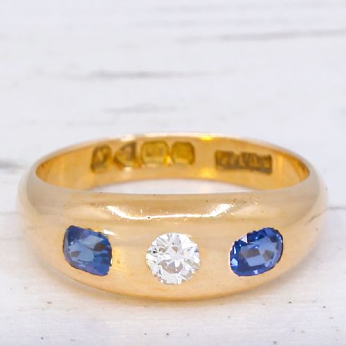 fig 2. An antique yellow gold gypsy band set with a central old cut diamond flanked by two oval blue sapphires.