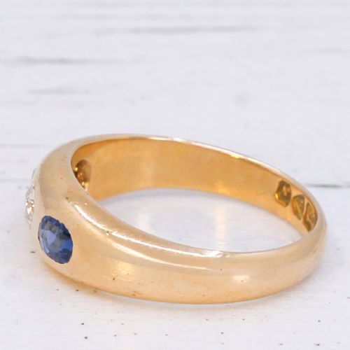 An antique yellow gold gypsy band set with a central old cut diamond flanked by two oval blue sapphires. View IV