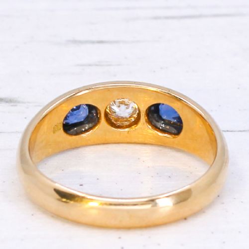 An antique yellow gold gypsy band set with a central old cut diamond flanked by two oval blue sapphires. View V