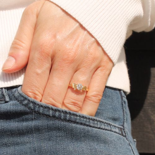 fig 1. A yellow gold Art Deco engagement ring featuring a central round old cut diamond flanked by geometric stepped shoulders set with small accent diamonds.