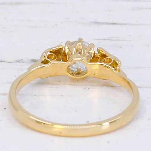 A yellow gold Art Deco engagement ring featuring a central round old cut diamond flanked by geometric stepped shoulders set with small accent diamonds. View IV