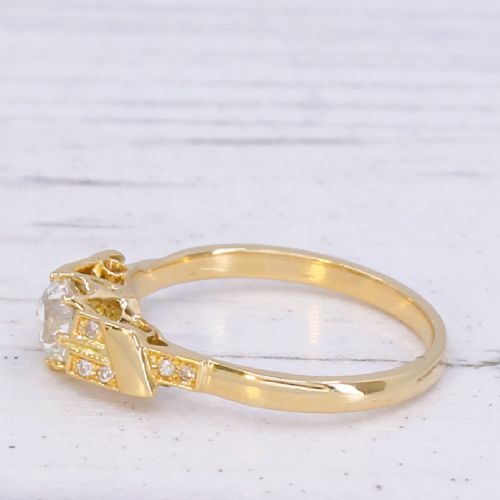 A yellow gold Art Deco engagement ring featuring a central round old cut diamond flanked by geometric stepped shoulders set with small accent diamonds. View V