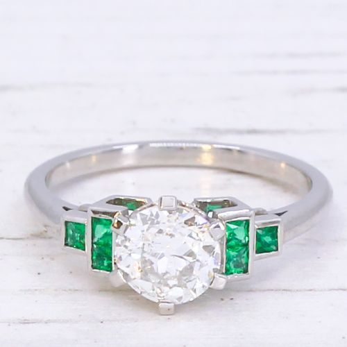 fig 2. A platinum ring set with a central round old European cut diamond flanked by channel-set green emerald shoulders.