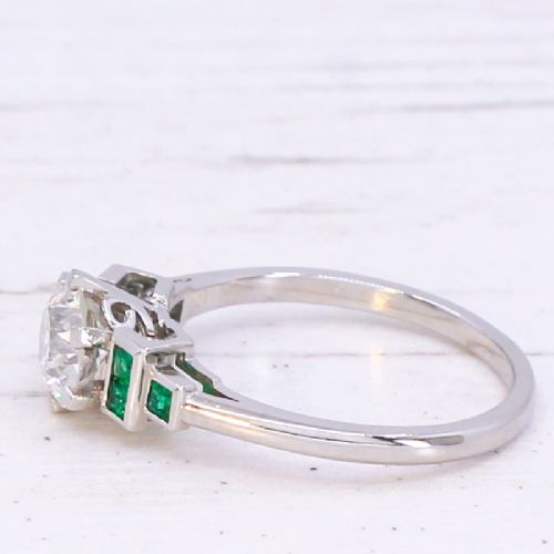 fig 3. A platinum ring set with a central round old European cut diamond flanked by channel-set green emerald shoulders.