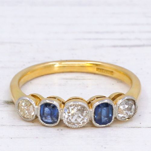 fig 2. An antique yellow gold ring set with five alternating old cut diamonds and cushion-shaped blue sapphires featuring millegrain details.