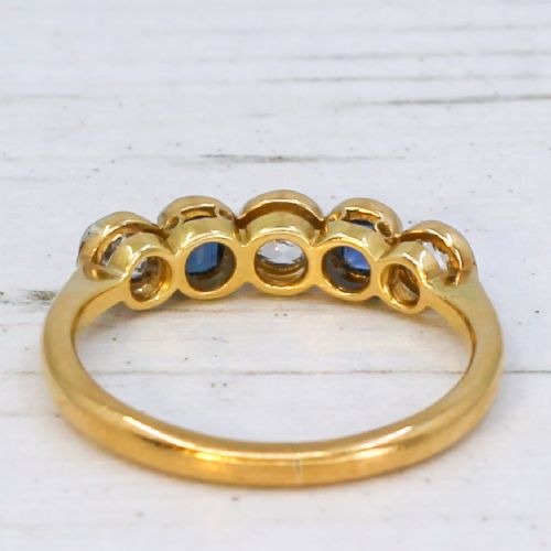 An antique yellow gold ring set with five alternating old cut diamonds and cushion-shaped blue sapphires featuring millegrain details. View V