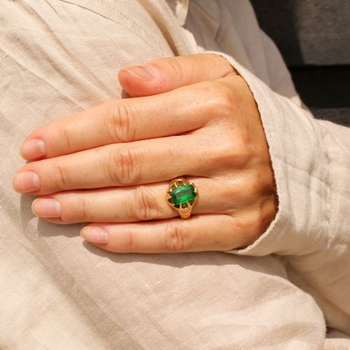 fig 1. An antique gold ring featuring a cushion-cut green tsavorite garnet held in multi-claw settings with scroll-engraved shoulders.