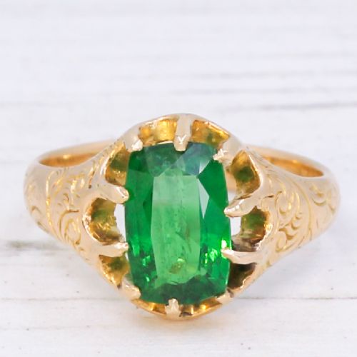 fig 2. An antique gold ring featuring a cushion-cut green tsavorite garnet held in multi-claw settings with scroll-engraved shoulders.