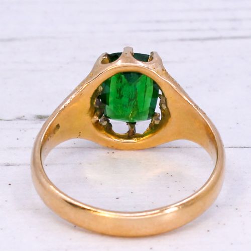 An antique gold ring featuring a cushion-cut green tsavorite garnet held in multi-claw settings with scroll-engraved shoulders. View V
