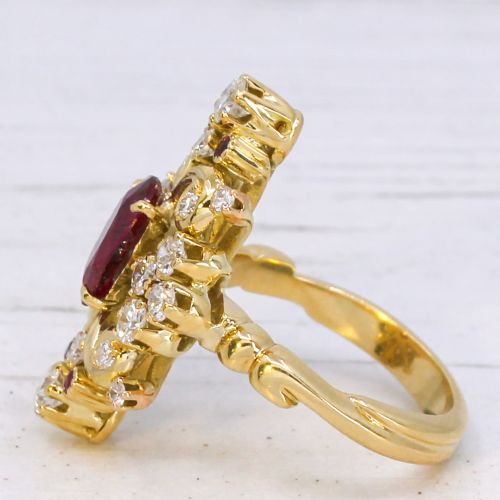 fig 3. A yellow gold vintage ring featuring an oval red ruby surrounded by openwork scroll motifs set with round diamonds and accent rubies.