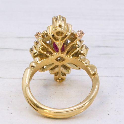 fig 4. A yellow gold vintage ring featuring an oval red ruby surrounded by openwork scroll motifs set with round diamonds and accent rubies.