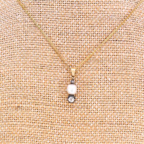 fig 2. An antique gold chain holding a vertical drop pendant featuring a natural pearl suspended between two bezel-set diamonds.