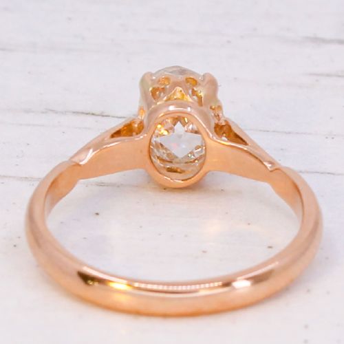 An Art Deco period rose gold ring featuring a central old oval cut diamond held in a claw setting with contoured shoulder details. View V
