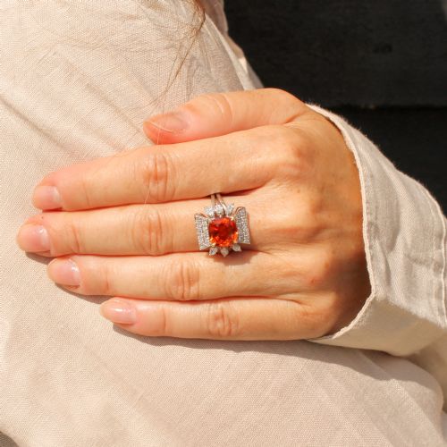 fig 1. A mid-century vintage cocktail ring featuring a cushion-cut orange garnet central gemstone flanked by pave and marquise diamond accents set in a white gold band.